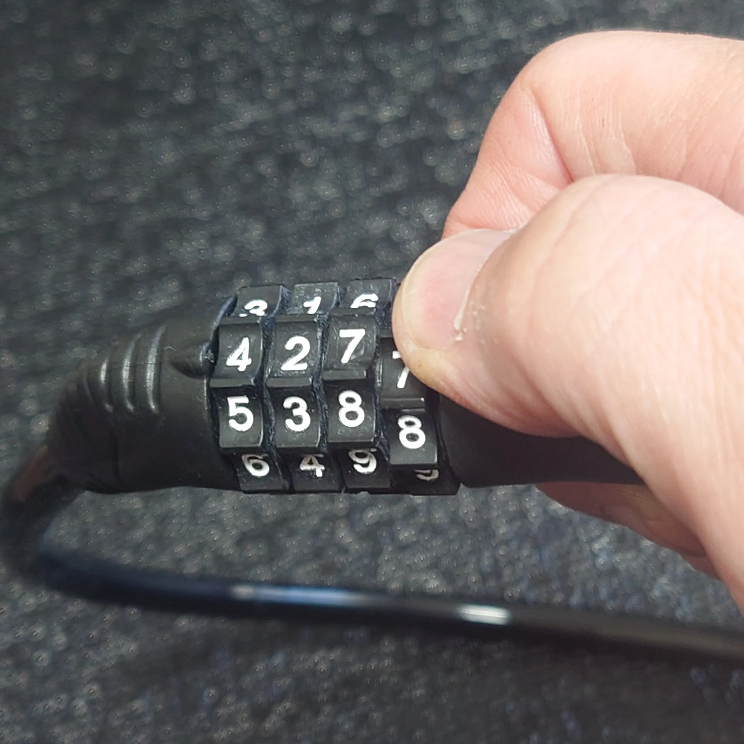 ワイヤーロックの暗証番号を合わせて解錠できるか確認している手元アップ