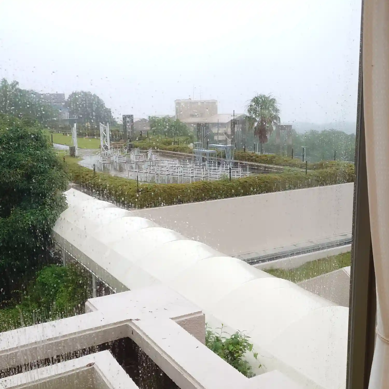 雨粒の付いた窓越しに眺めるエクシブ伊豆の屋外スペース