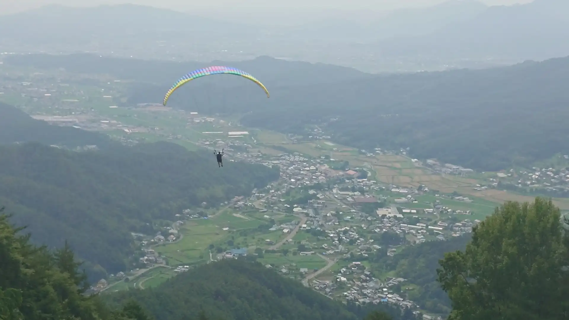 青木村の上空をゆっくり進んでいくタンデムパラグライダー