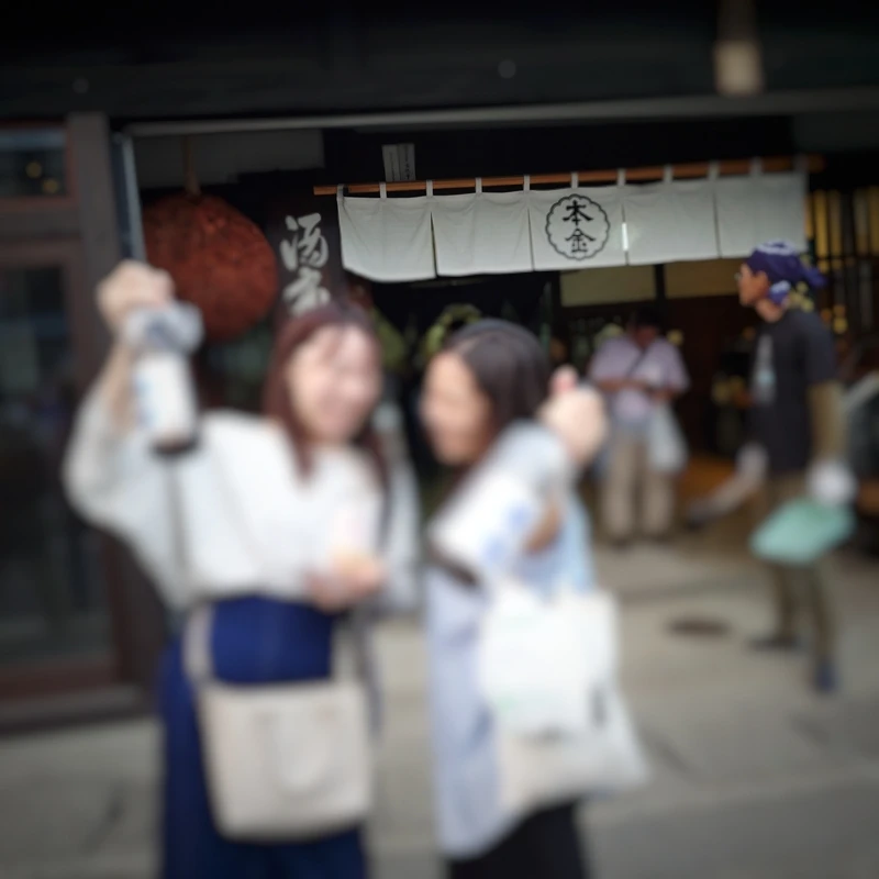 本金前で日本酒を掲げる笑顔の女性参加者