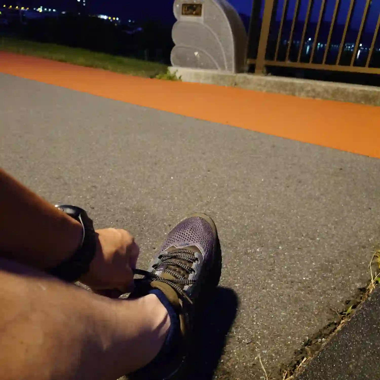 早朝5時過ぎの諏訪湖畔でランニングシューズを履く場面