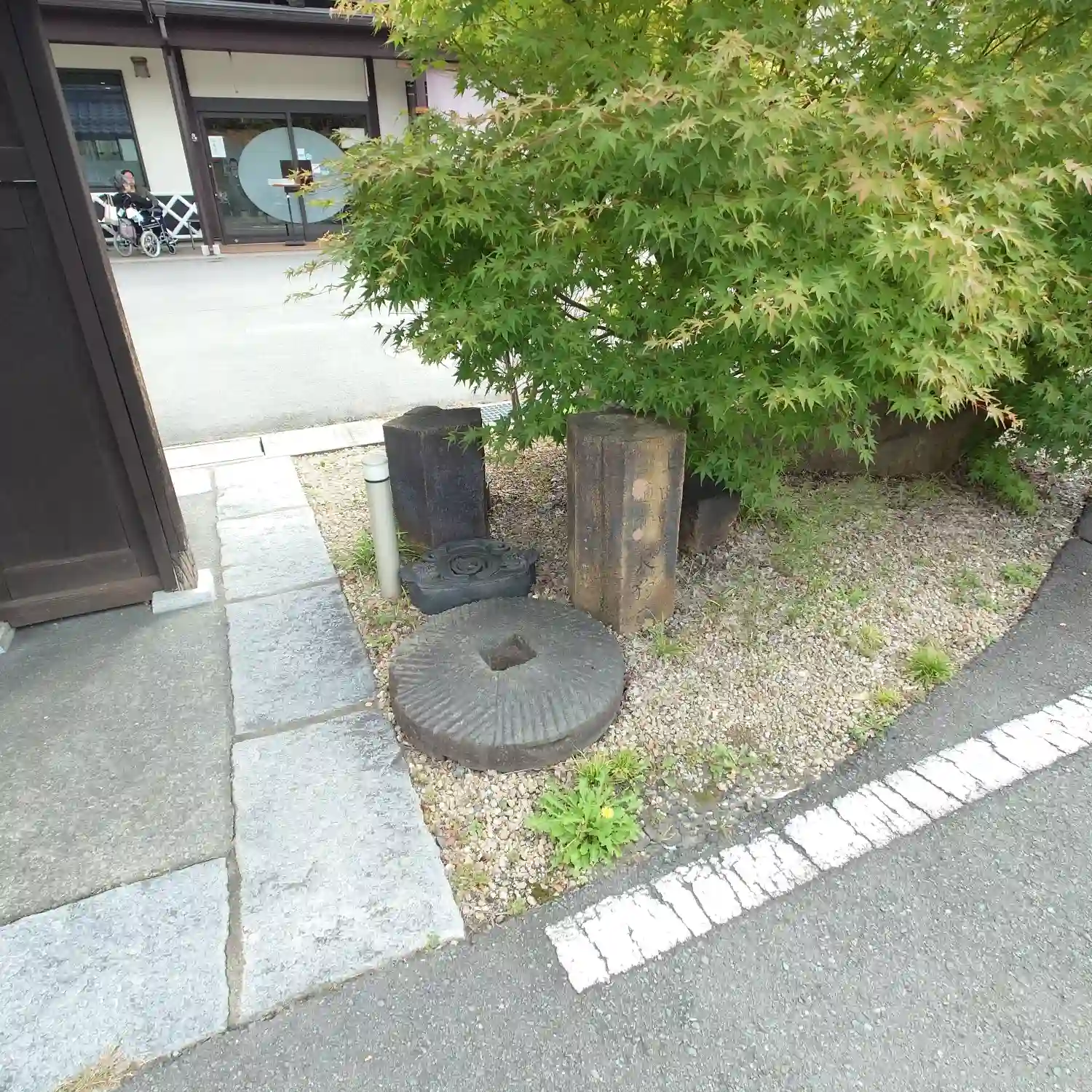 信州蕎麦 草笛 上田お城前店の入口に置かれた石臼と植栽